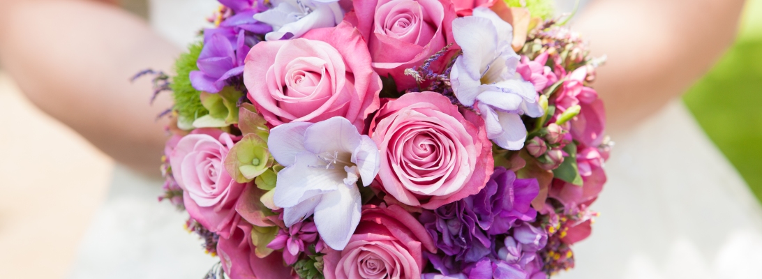 Rosa Rosen mit violetten und weißen Blüten kombiniert.